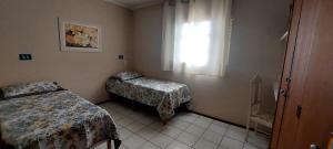 a small room with two beds and a window at Pousada Palmeira in Viracopos