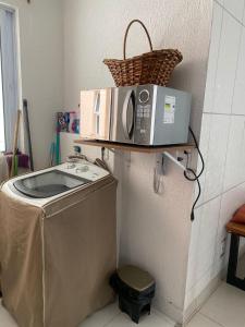 a microwave sitting on a shelf above a washing machine at Apartamento em Ilhéus próximo as Praias in Ilhéus