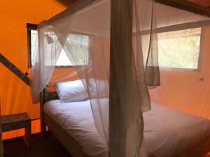 Bungalows - Càmping El Solsonès في سولسونا: غرفة نوم مع سرير مظلة مع نافذة