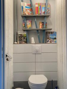 a bathroom with a toilet and a shelf with books at Escale en Correze in Sadroc