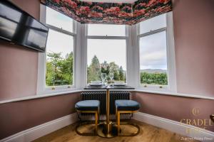 a dining room with a table and two chairs in front of a window at Fair Rigg by Cradel Haus - Ultra Luxury Lakes Holiday Homes, Pet Friendly, Parking & EV Plug in Bowness-on-Windermere