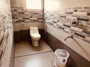 a bathroom with a toilet and brick walls at Hotel Kanchani - A Majestic Mountain Retreat in Manāli
