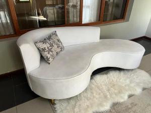 a white couch with a pillow on top of a rug at TR GUEST HOUSE in Matola