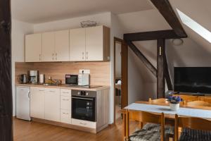 a kitchen with white cabinets and a kitchen table with a microwave at Apartmán V PODKROVÍ in Horní Planá