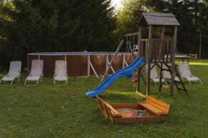 a playground with a slide and chairs in a yard at Apartmán V PODKROVÍ in Horní Planá