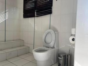 uma casa de banho com um WC com tampa para cima em TR GUEST HOUSE em Matola