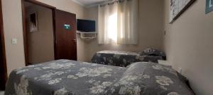 a hotel room with two beds and a window at Pousada Palmeira in Viracopos
