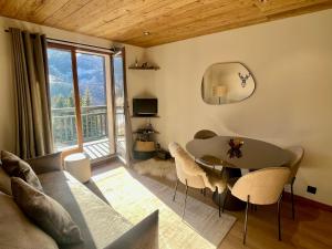 ein Wohnzimmer mit einem Tisch und einem großen Fenster in der Unterkunft Nid de charme au pied des pistes in Saint-Martin-de-Belleville