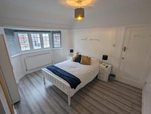 1 dormitorio con 1 cama y 2 ventanas en The Manor Guest House in Wembley, en Londres