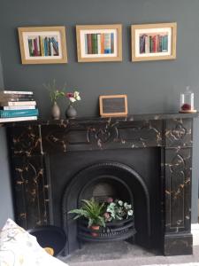 a black fireplace with flowers on top of it at Hebble End View B&B in Hebden Bridge