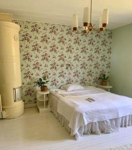 1 dormitorio con cama y papel pintado con motivos florales en Lantligt boende nära Kastelholms golf och Smakbyn, 