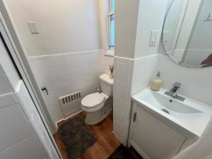 Baño blanco con aseo y lavamanos en 7-A Diamond in Yonkers, en Yonkers