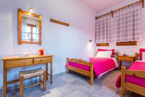 1 dormitorio con 2 camas, escritorio y espejo en Nikolaos studios apartments en Skopelos Town