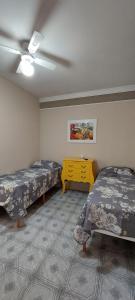 Pokój z 2 łóżkami i żółtą komodą w obiekcie Pousada Palmeira w Viracopos