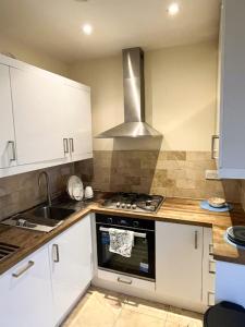 a kitchen with white cabinets and a stove top oven at Apartment moments from Hyde Park in London