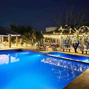 a swimming pool at night with lights on a house at Blue Palm Resort Ghana in Abia