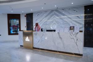 a woman standing behind a counter in a lobby at Sanam Hotel Suites - Riyadh in Riyadh