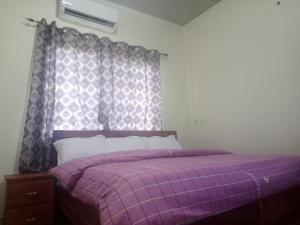 a purple bed with a purple blanket and a window at Hotel Lily in Accra