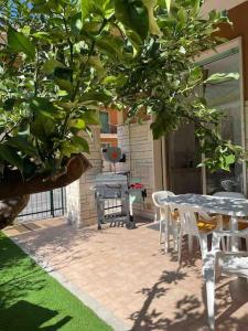 een patio met een tafel en stoelen en een boom bij Trilocale con incantevole giardino in Pietra Ligure