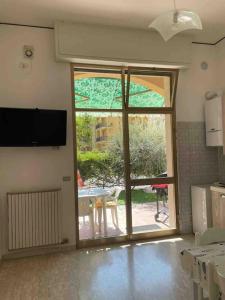een kamer met een open deur naar een patio met een tafel bij Trilocale con incantevole giardino in Pietra Ligure