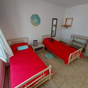 2 Betten in einem Zimmer mit einer roten Decke in der Unterkunft Casa en El Paraíso Tandil in Tandil