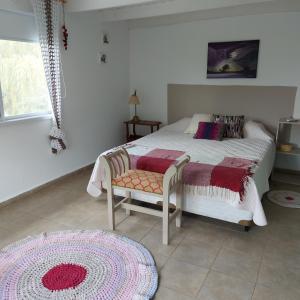 ein Schlafzimmer mit einem Bett, einem Stuhl und einem Teppich in der Unterkunft Casa en El Paraíso Tandil in Tandil