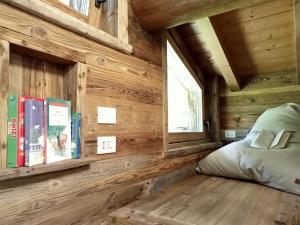 1 dormitorio con paredes de madera, 1 cama y ventana en Baita La Piana - Carona, en Carona