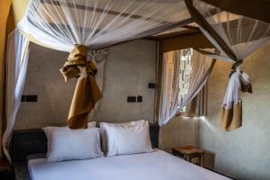 sypialnia z łóżkiem z zasłonami powyżej w obiekcie Baobab Bungalows w mieście Jambiani