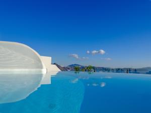 a pool of water with a clear blue sky at Nostos Apartments in Oia