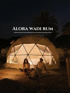 Un uomo e una donna seduti in una tenda di notte di Alora Wadi Rum Luxury a Wadi Rum