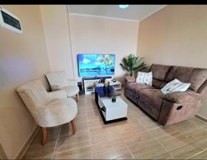 ein Wohnzimmer mit einem Sofa, einem Stuhl und einem TV in der Unterkunft Departamento completo sector aeropuerto La Serena in La Serena