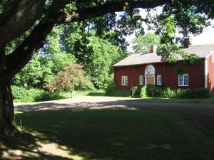 un granero rojo con un árbol delante de él en Romantic villa on old Mansion en Säffle