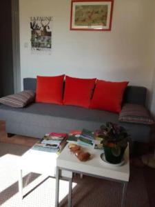 Au clos des Varnelles في Revigny-sur-Ornain: غرفة معيشة مع أريكة مع وسائد حمراء وطاولة
