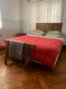a bedroom with a large bed with red sheets and yellow pillows at Casa Verde in Valparaíso