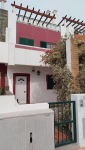 un edificio blanco con una puerta roja y una valla en The South Sunny House - A Casa a Sul, en Olhão