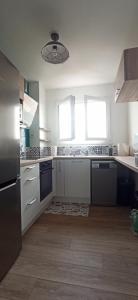 uma cozinha com armários brancos e uma grande janela em Appartement cosy route des plages em Lorient