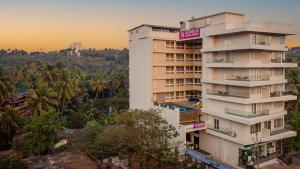 Un grand bâtiment blanc avec des panneaux sur son côté dans l'établissement Regenta Place Vasco Goa, à Marmagao