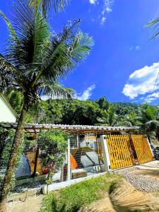 a palm tree in front of a house with a building at Camping Mill Off Adventure in Paraty