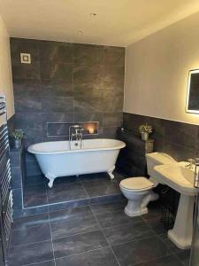 a bathroom with a tub and a toilet and a sink at The Barn, Romantic country getaway in Dyserth