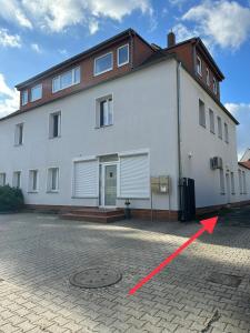 a large white building with a red arrow in front of it at Cosy Nest - Apartment by Comfort Housing in Falkensee