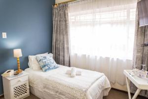 a bedroom with a white bed and a window at Rozendal Guest House in Centurion