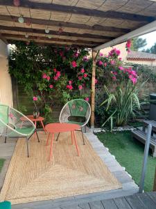 2 chaises et une table sur une terrasse fleurie dans l'établissement LA PASSIFLORE, à La Londe-les-Maures