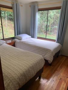 twee bedden in een kamer met twee ramen bij Casa Orilla Lago Cólico in Cunco