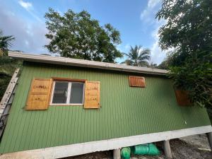 a green house with wooden shutters and a window at Rockxy HOSTEL BY JR in Providencia