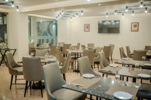 Regenta Place Vasco Goa في Marmagao: غرفة طعام مليئة بالطاولات والكراسي