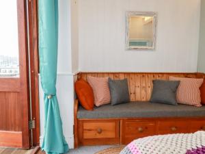 Habitación con banco con almohadas y ventana en Zawn Nook, en Falmouth