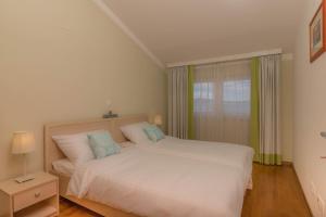 a bedroom with a large white bed and a window at Simba Apartman 59 in Selce