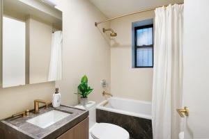 een badkamer met een wastafel, een toilet en een spiegel bij 76-1D Brand New 4BR 3BTH UES Doorman Gym in New York