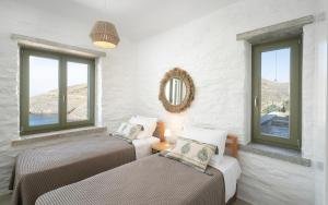 two beds in a room with two windows at Triad Villas in Ioulis