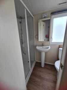 ein Bad mit einem Waschbecken, einer Dusche und einem WC in der Unterkunft Happy Days Caravan Primrose Valley in Filey